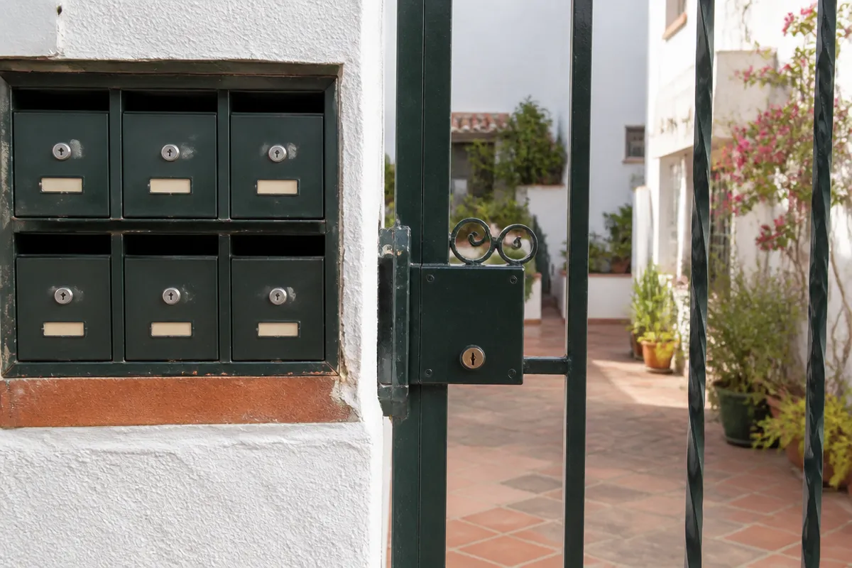 Buzón comunitario y cancela metálica en un patio de Murcia para apertura