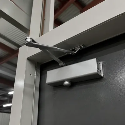 Brazo de muelle cierrapuertas instalado en el dintel de una puerta en Murcia